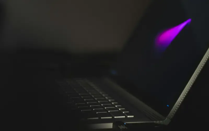 A laptop keyboard lit only by the screen in a dark room