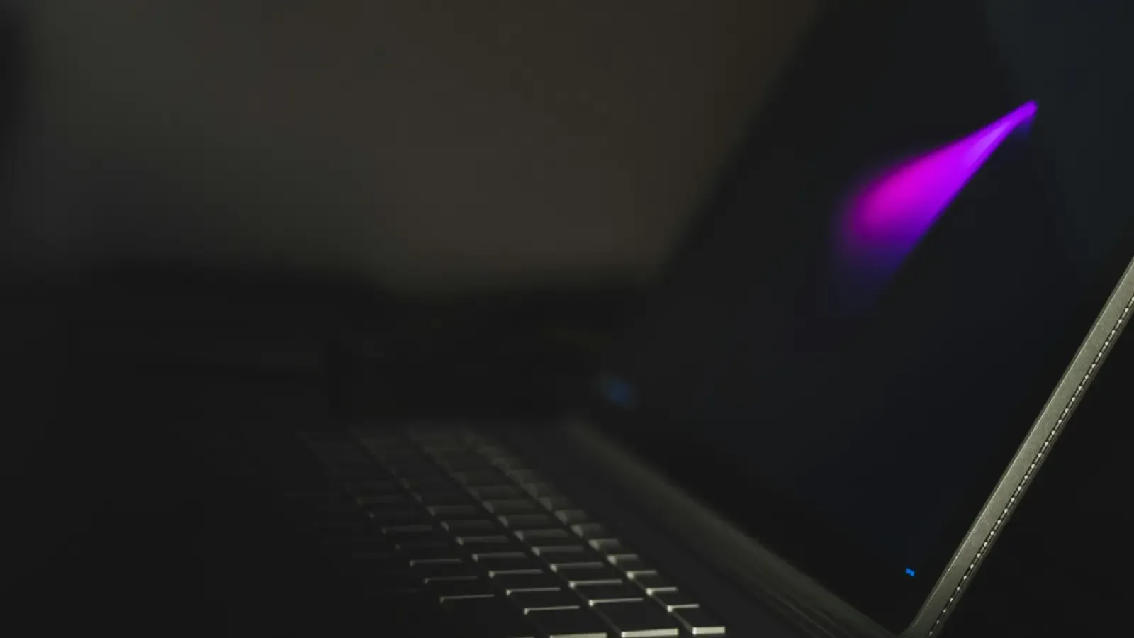 A laptop keyboard lit only by the screen in a dark room