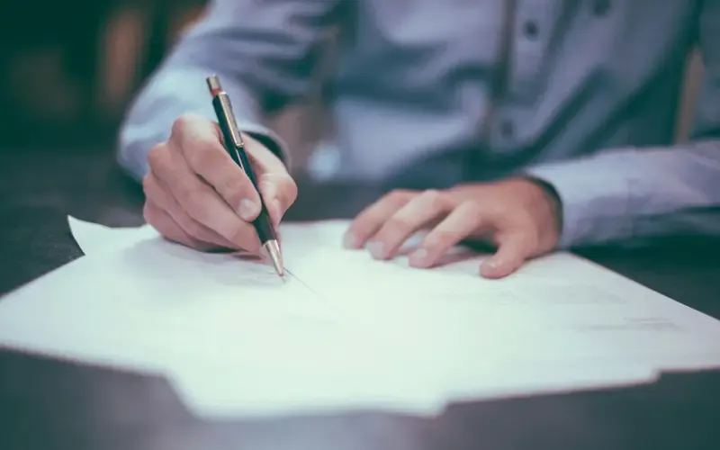 A pair of hands annotating a printed document with a pen