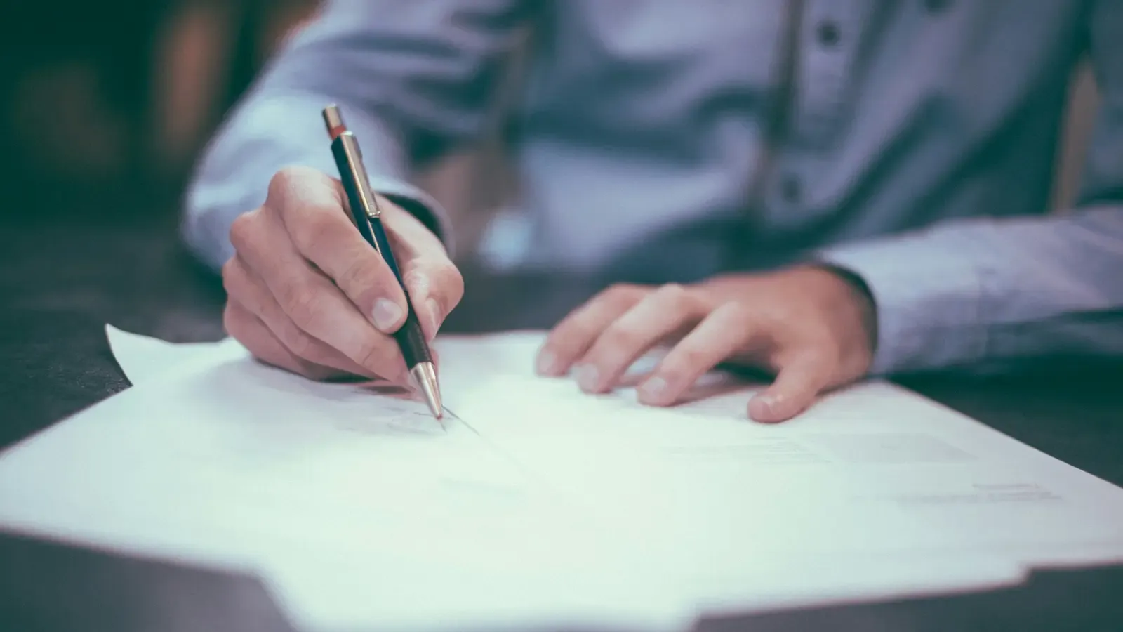 A pair of hands annotating a printed document with a pen