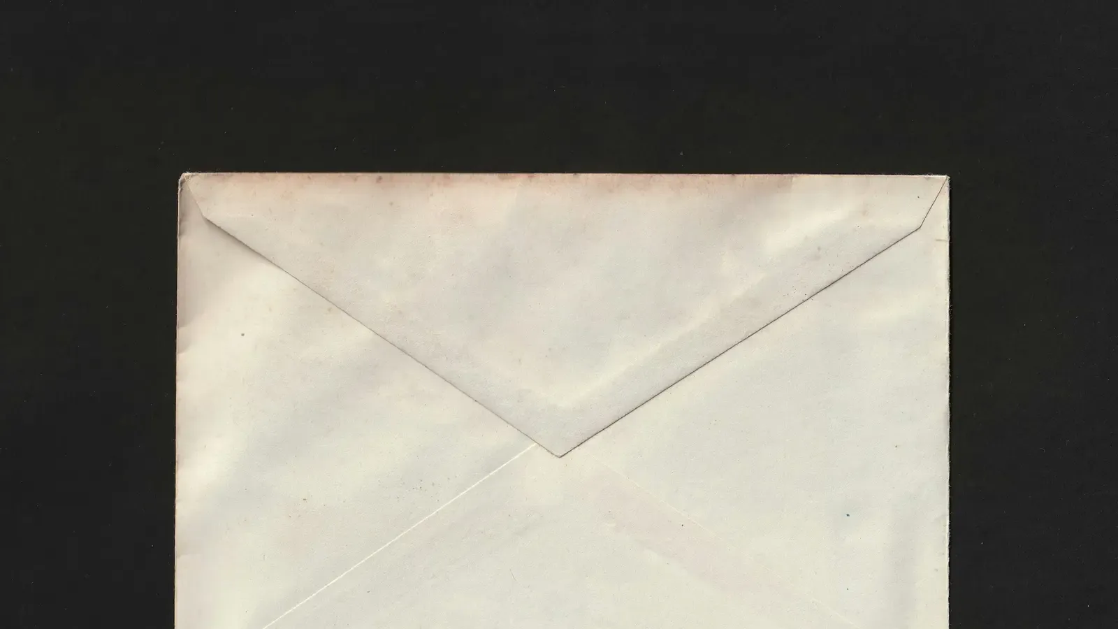 A single sealed white envelope on a black surface
