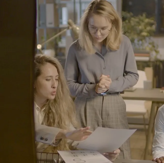 Three colleagues talking over a desk in a bright office