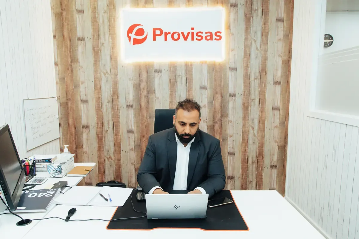 Inder Singh working at a desk beneath an illuminated Provisas sign